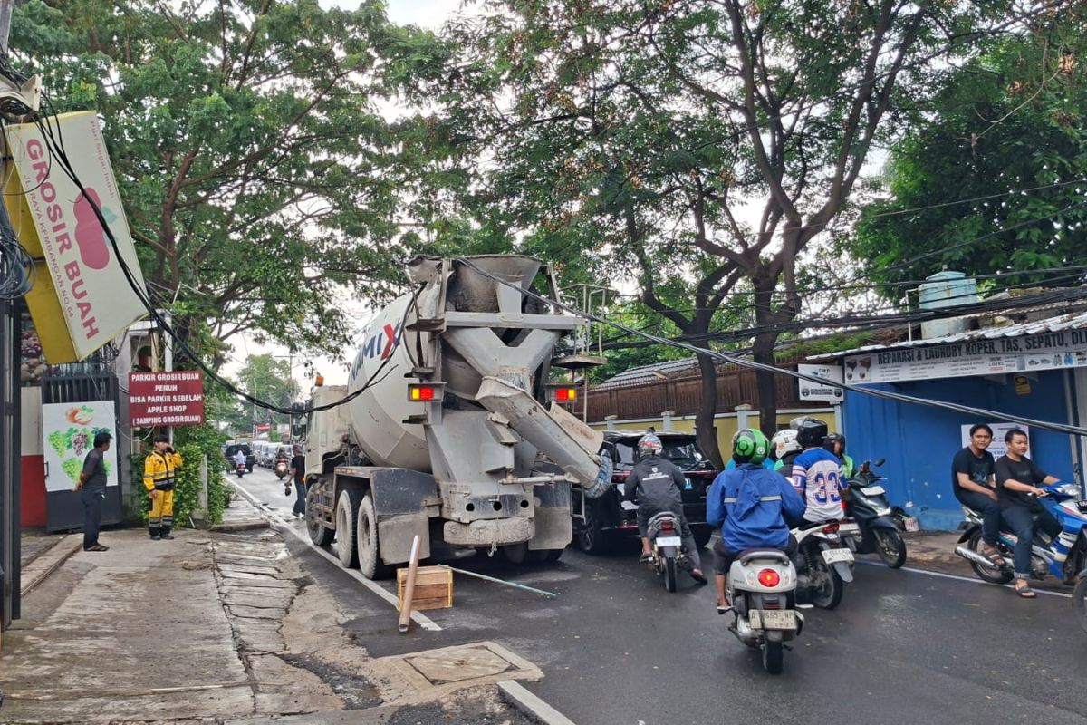 Concrete mixer truck caught on utility cables in West Jakarta