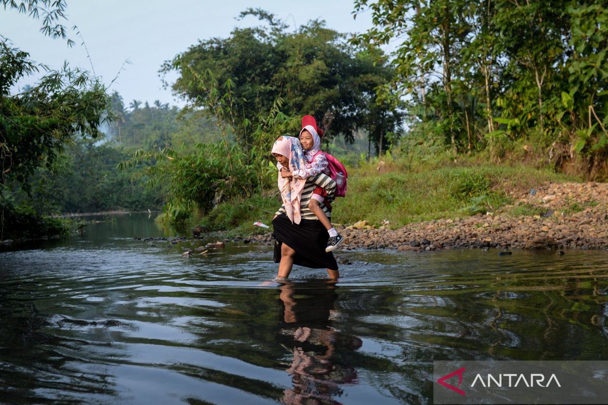 Without a bridge, primary school students rely on river crossing to reach school