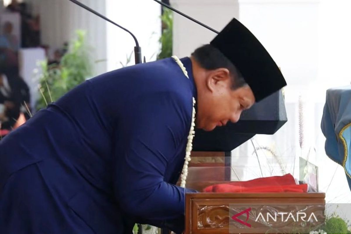 President kisses Red and White flag before handing it to bearer