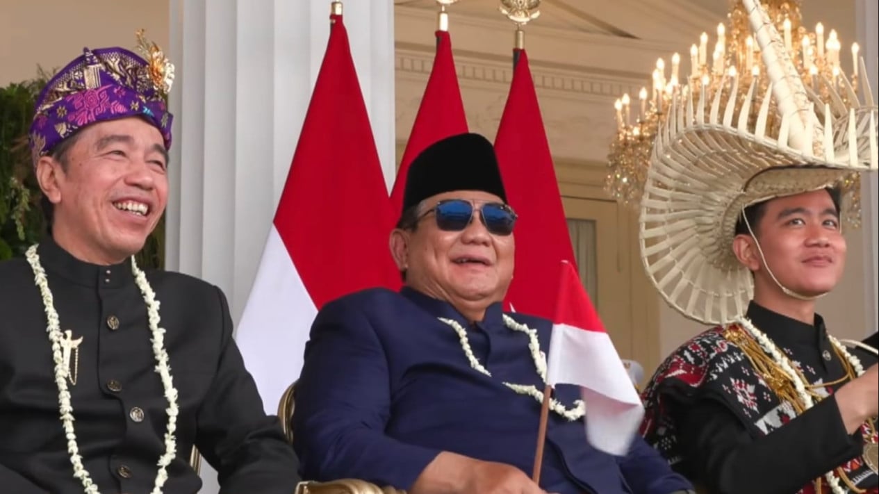 Prabowo Seated Between Jokowi and Gibran, Smiling While Watching Jet Display at the Palace