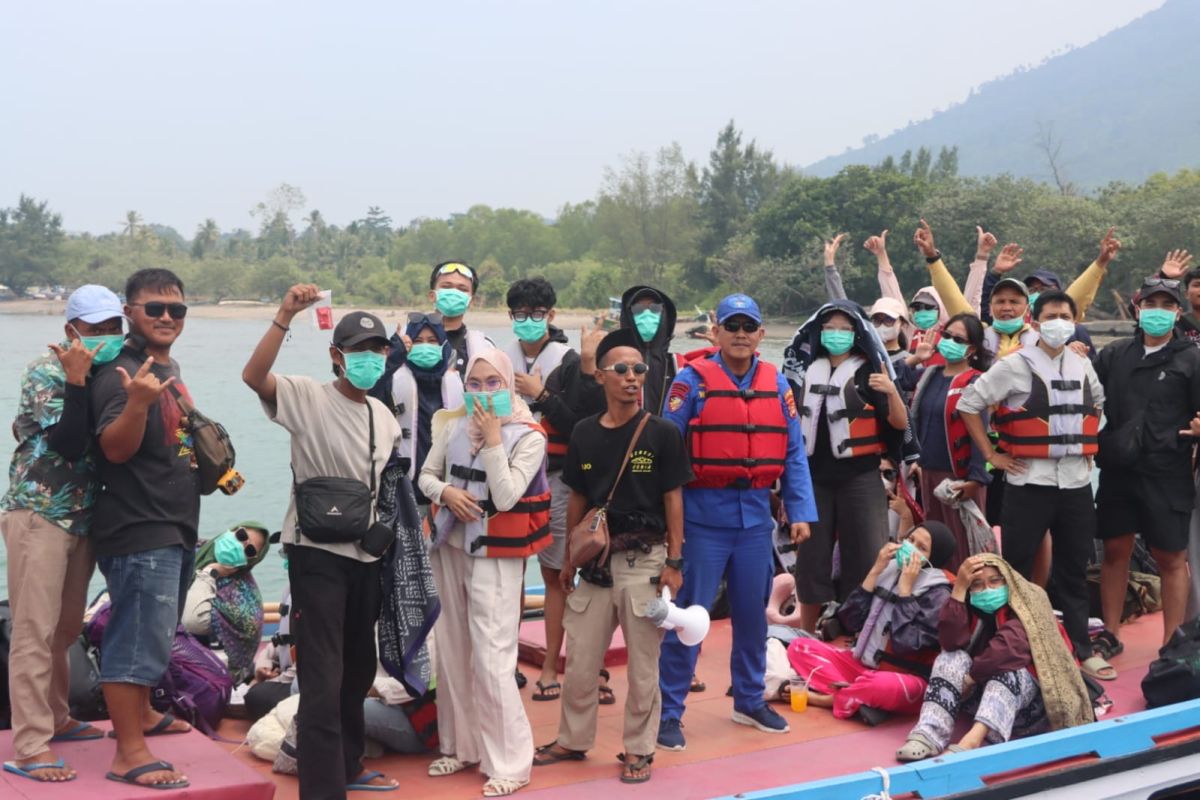 Officers distribute masks and remind tourists to adhere to Krakatau safety zones